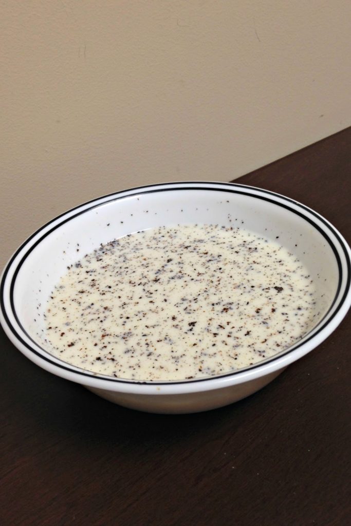 Bowl of milk mixed with raw sugar and ground pepper simmered over the stove